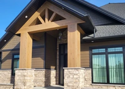 Modern exterior entryway of home with stained wood beams and stone accents