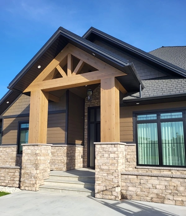 Modern exterior entryway of home with stained wood beams and stone accents